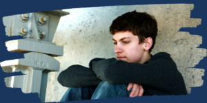 a teen sitting outside with his hands on his knees